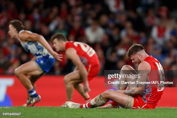 Peter Ladhams of the Swans twists his ankle in a ruck contest during the round 10 AFL match between North Melbourne Kangaroos and Sydney Swans at...