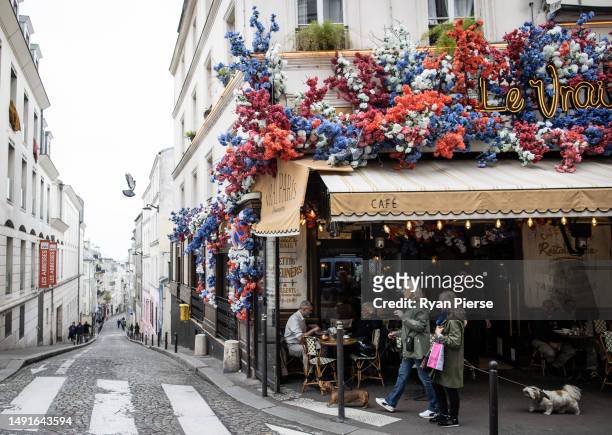 People walk past a restaurant in Montmartre on May 15, 2023 in Paris, France.