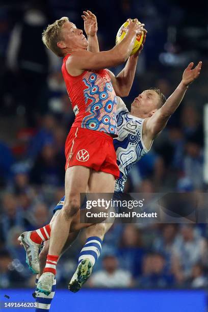 Isaac Heeney of the Swans marks the ball under pressure from Jack Ziebell of the Kangaroos during the round 10 AFL match between North Melbourne...