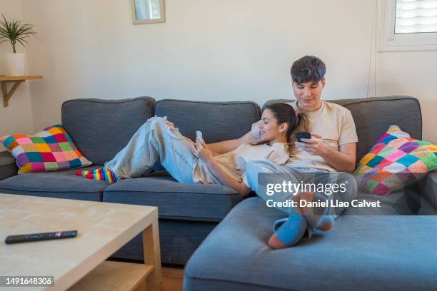couple using their mobile phones while relaxing at home. - casa calvet stock pictures, royalty-free photos & images