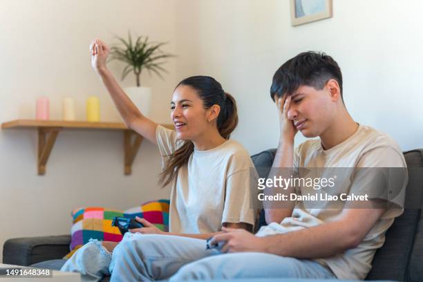 woman celebrating victory while playing video games with her boyfriend at home. - casa calvet stock pictures, royalty-free photos & images