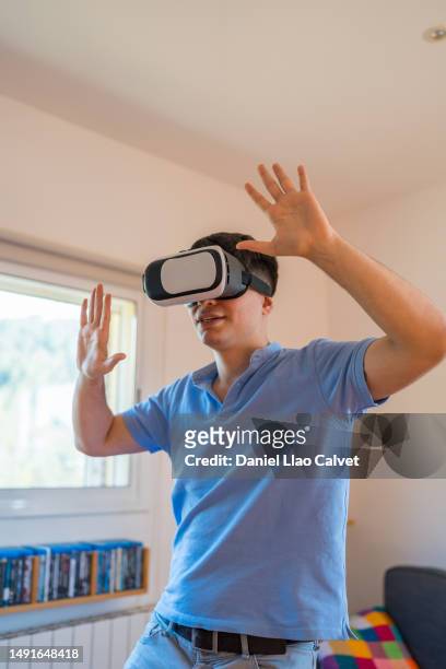 man playing video games with virtual reality headset at home. - casa calvet stock pictures, royalty-free photos & images