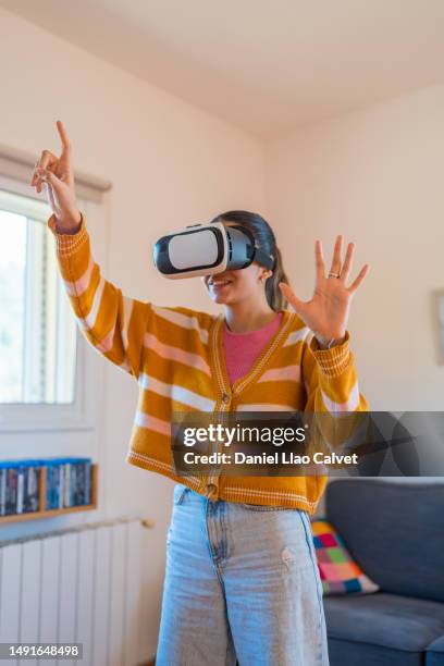 young woman experiencing virtual reality with vr glasses at home. - casa calvet stock pictures, royalty-free photos & images