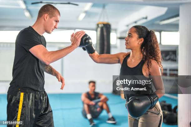 junge hispanische frau trainiert mit einem kaukasischen boxtrainer in einem boxclub - kickboxen stock-fotos und bilder