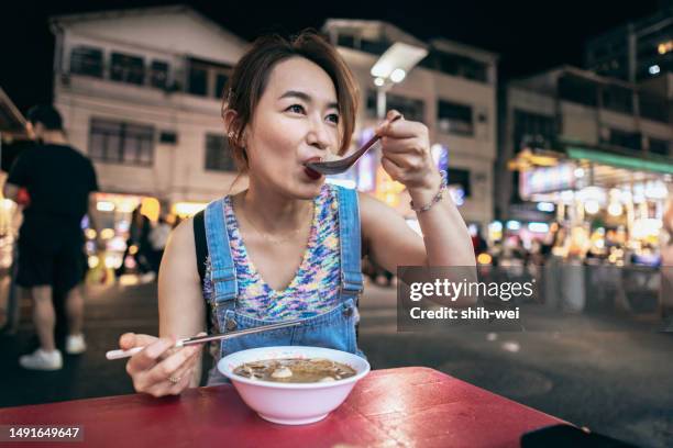 asian women visit local night markets during their journey, finding it interesting and trying local delicacies. - taiwan night market stock pictures, royalty-free photos & images