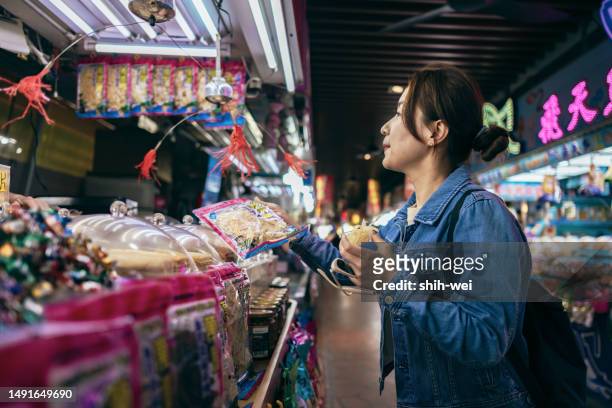 asiatische frauen besichtigen während ihrer reise lokale märkte, finden es interessant und probieren lokale köstlichkeiten. - taiwanese ethnicity stock-fotos und bilder