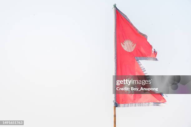 the national flag of nepal against white sky. the flag of nepal is the only national flag in the world that is not rectangular. - nepali flag stock-fotos und bilder