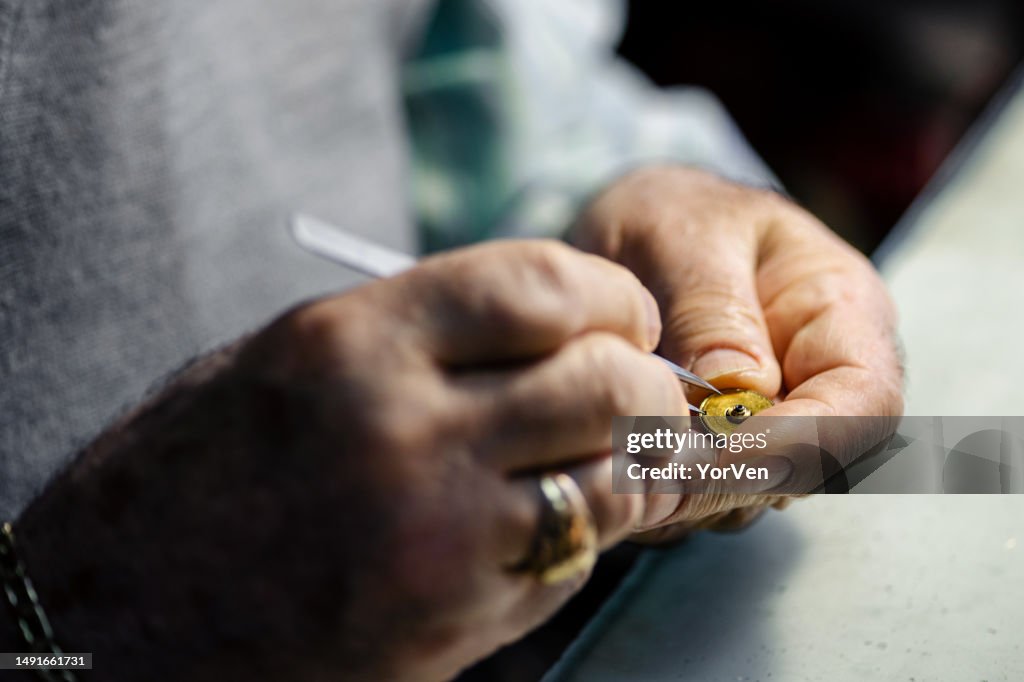 Close up of senior watchmaker repairing watches at his workshop .