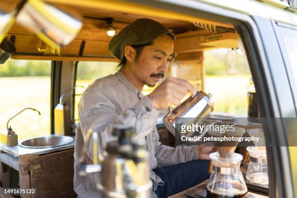 ein mann, der kaffee in seinem mobilen kaffeewagen kocht, der im freien geparkt ist - filterkaffee stock-fotos und bilder