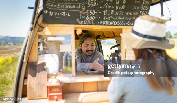 a woman buys coffee from a small business mobile coffee van in the countryside - iwate prefecture stock pictures, royalty-free photos & images