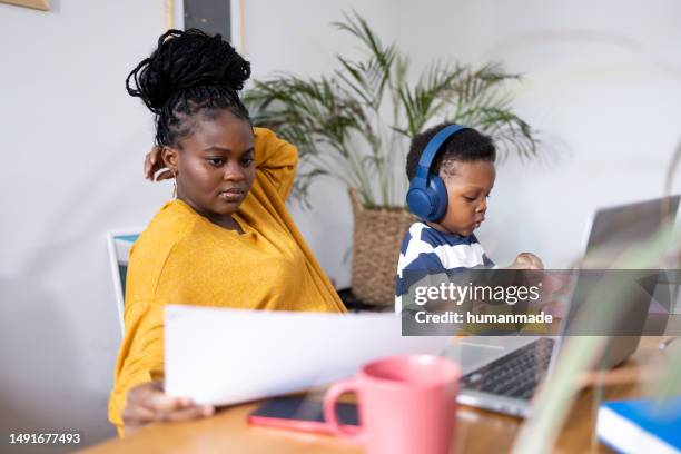 young beautiful african american woman working from home with her toddler son - 21 years later what peace stock pictures, royalty-free photos & images
