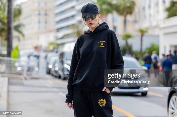Katya Tolstova wears black hoody, jogger pants, cap, sunglasses during the 76th Cannes film festival on May 19, 2023 in Cannes, France.