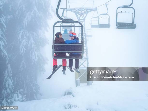 young multiracial skiers smiling on ski lift, misty day - couple ski lift stockfoto's en -beelden