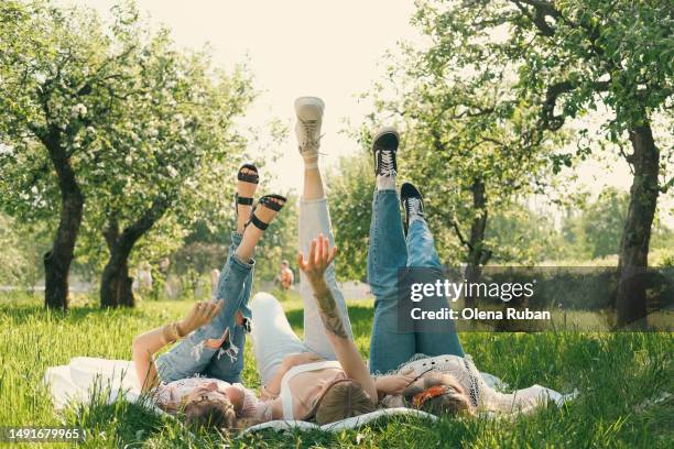 young women lying with legs up in orchard garden. - feet up stock pictures, royalty-free photos & images