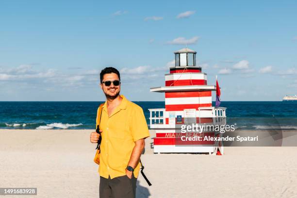 happy smiling man in a yellow shirt at south beach, miami, usa - miami beach ストックフォトと画像