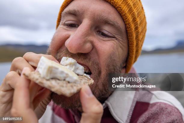 porträt eines mannes, der käse auf crackern am see hat, norwegen - eating cheese stock-fotos und bilder