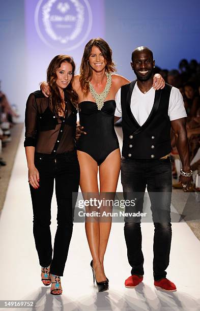 Model escorts designers Stephanie Theis Fajardo and Kevin Fitzpatrick on the runway for the Cote D'Or Swimwear collection during the Anna Kosturova,...