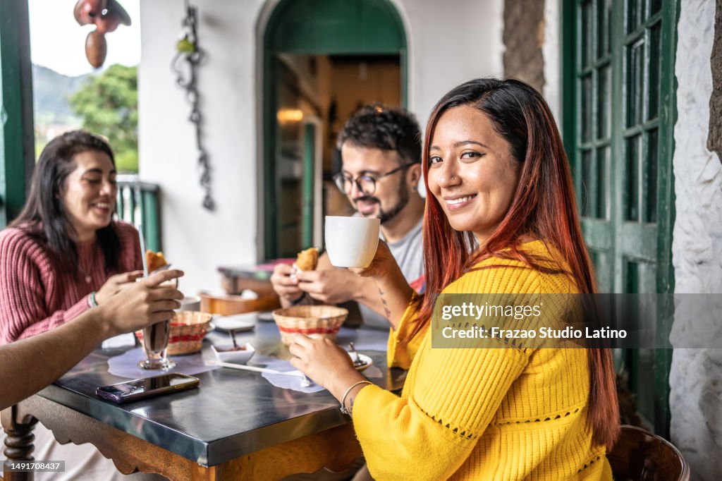 Porträt einer jungen Frau, die mit Freunden in einem Café isst
