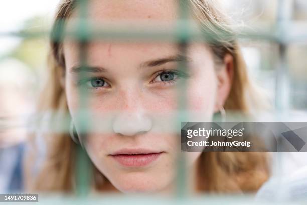 close up portrait of young woman through wire fencing - mesh fence stock pictures, royalty-free photos & images