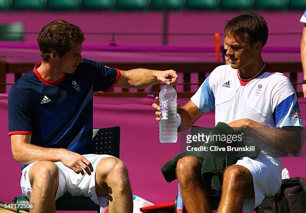 Andy Murray and Ross Hutchins of Great Britain take a break during a practice session ahead of the 2012 London Olympic Games at the All England Lawn...