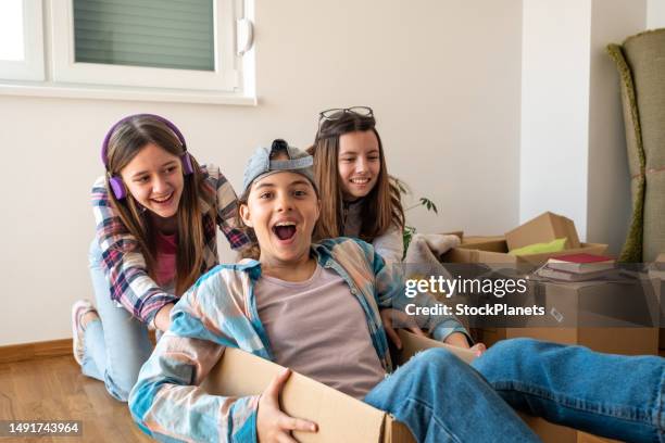 three teenage girls ride in a box in a new apartment while unpacking. - boys and girls club of america stock pictures, royalty-free photos & images