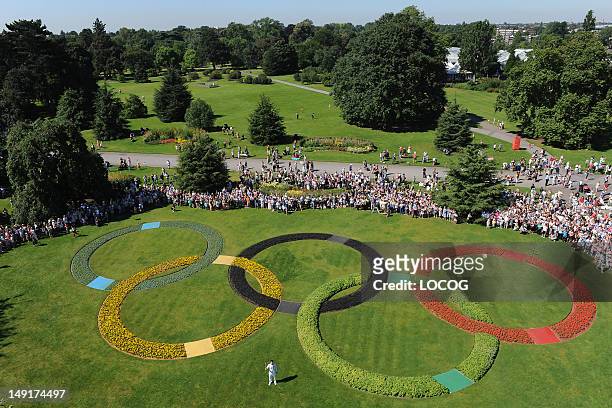 In this handout image provided by LOCOG, Torchbearer 048 Oliver Golding holds the Olympic Flame in between the Olympic Rings at Kew Gardens on July...