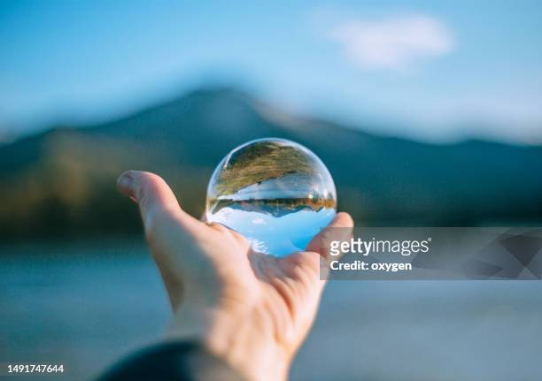 hand of woman holding lens ball at beach againstaltai mountains and katun' river, sunset orb - focus lens stockfoto's en -beelden