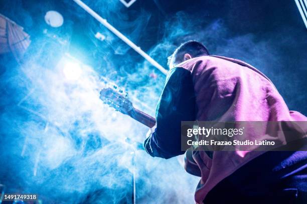 rear view of a musician man playing guitar in a music concert - gitarist stockfoto's en -beelden