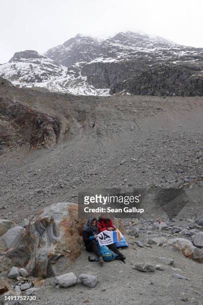 Climate activists with a "yes" banner wait below a moraine of the receding Morteratsch glacier prior to a gathering to campaign for an upcoming...