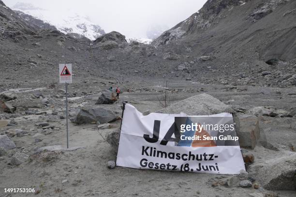 Banner that reads "Yes - Climate Protection Law 18. June" stands below the receding Morteratsch glacier during a gathering to campaign for an...