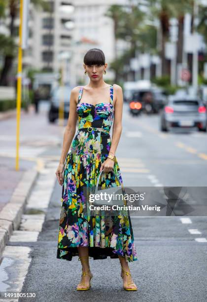 Katya Tolstova wears dress with floral print, turquoise asymmetric bag, heeled sandals during the 76th Cannes film festival on May 20, 2023 in...