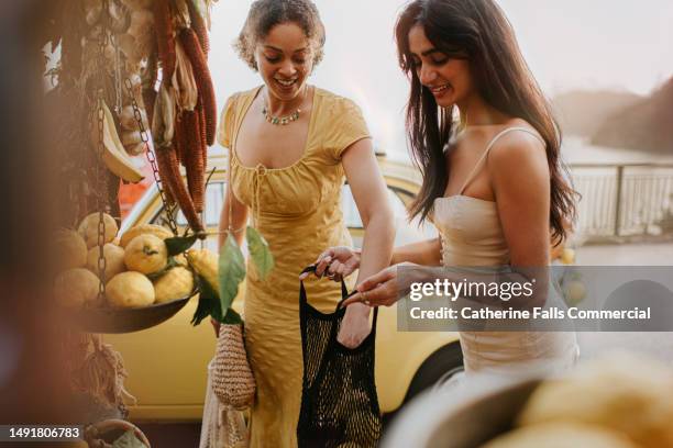 two woman shop at an italian fruit stall - italien stock-fotos und bilder