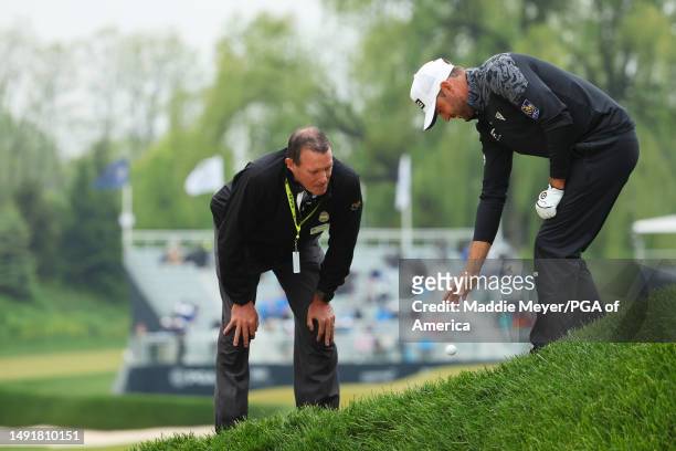 Corey Conners of Canada takes a drop as PGA Rules Official Mike Raby looks on after Conners' ball was imbedded on the 16th hole during the third...
