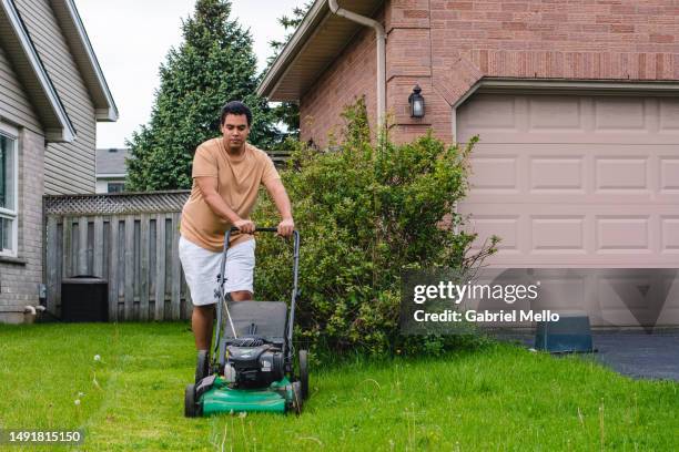 man mowing the grass of his backyard - cortar relva imagens e fotografias de stock