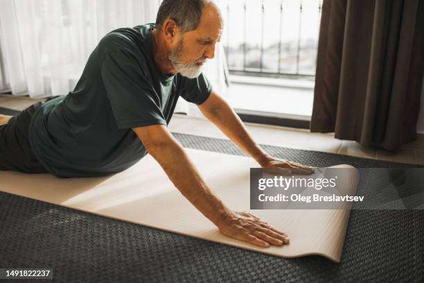 aged man with back problems doing rehabilitation stretching - sciatica stock pictures, royalty-free photos & images