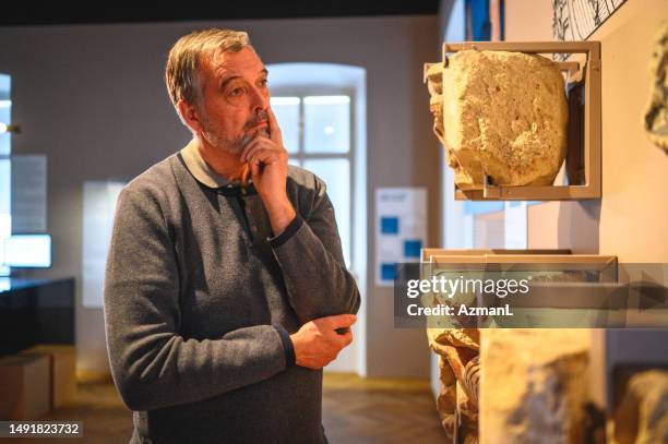 male third age university student looking at  a sculpture detail - museum visit stock pictures, royalty-free photos & images