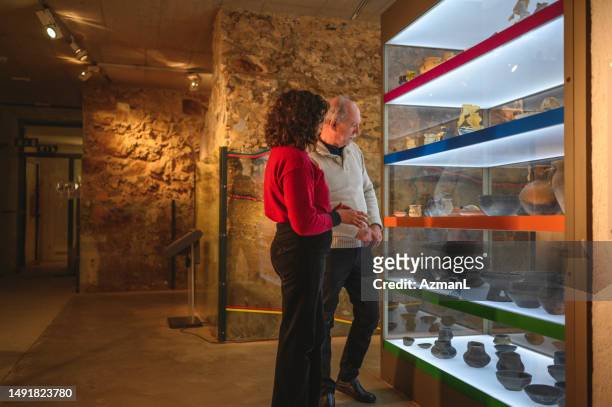 charming senior couple at the museum - vitrinekast stockfoto's en -beelden