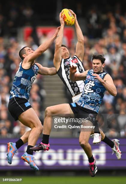 Brody Mihocek of the Magpies marks over Jacob Weitering and Mitch McGovern of the Blues during the round 10 AFL match between Carlton Blues and...