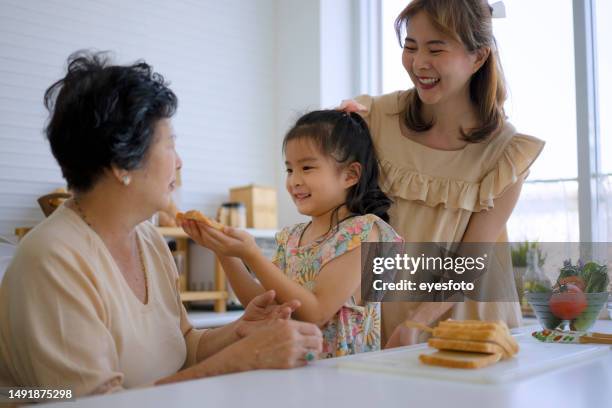 grandmother, mother and granddaughter prepare food in the kitchen. - sandwich generation stock pictures, royalty-free photos & images