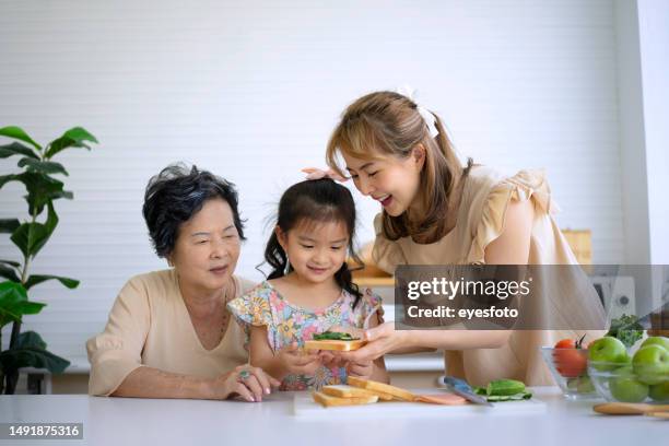 grandmother, mother and granddaughter prepare food in the kitchen. - asian granny pics 個照片及圖片檔