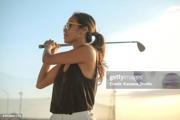 mujer asiática segura de sí misma swinging golf club - putting on sunglasses fotografías e imágenes de stock