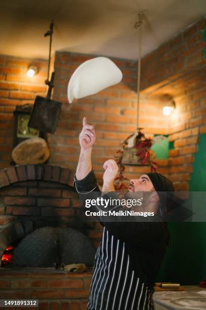 pizza chef showing his skills throwing pizza dough - pizza chef stock pictures, royalty-free photos & images