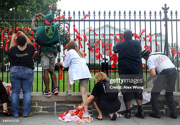 Activists tie fake and real bank notes and prescription drug bottles on the White House fence with red ribbons as he participates in a civil...