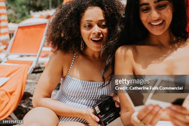 two young woman on holiday view photographs from an instant camera - body issue celebration party stock pictures, royalty-free photos & images