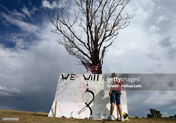 Girl signs a message board at a memorial across the street from the Century 16 movie theatre July 24, 2012 in Aurora, Colorado. The memorial was...