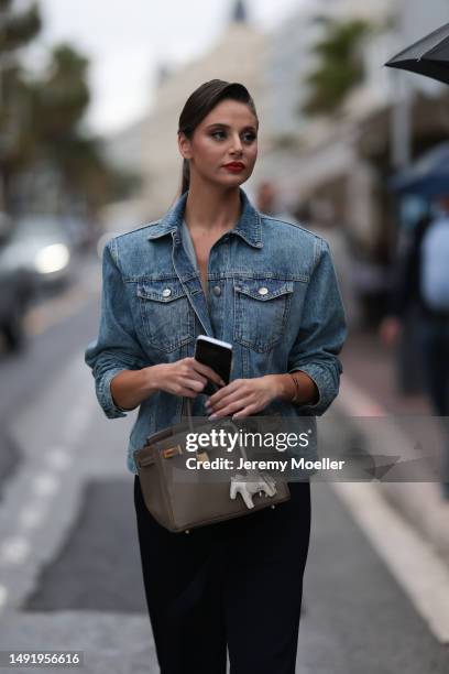 Carina Zavline seen wearing a blue jeans jacket, black wide pants, beige brown Hermes Kelly bag during the 76th Cannes film festival on May 20, 2023...
