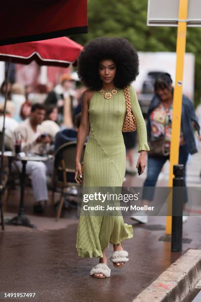 Film Festival Guest seen wearing a a long lime yellow dress and white puffer sandals, a flower chain and a brown statement bag during the 76th Cannes...