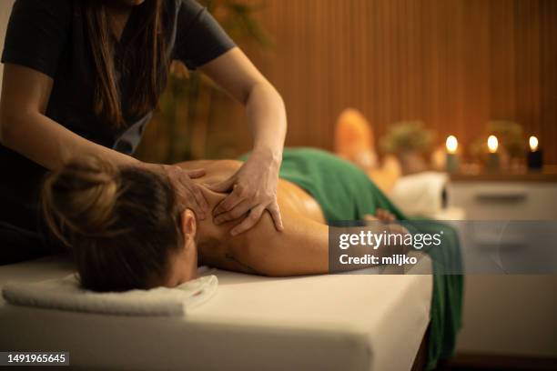 mujer joven recibiendo masaje de hombros y espalda en centro de spa - mesa de masajes fotografías e imágenes de stock