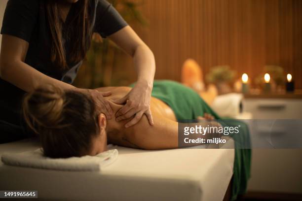 young woman receiving shoulder and back massage in spa center - massage table stock pictures, royalty-free photos & images