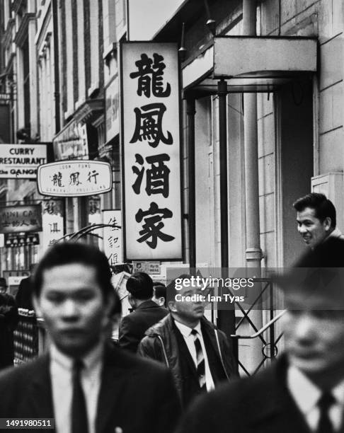 Pedestrians passing Chinese restaurants and shops in Chinatown, on Gerrard Street, in the West End of London, England, circa 1970.